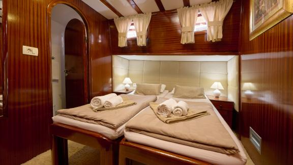 A luxurious cabin on the Gulet Linda with two single beds, elegant wooden walls and cosy lighting.